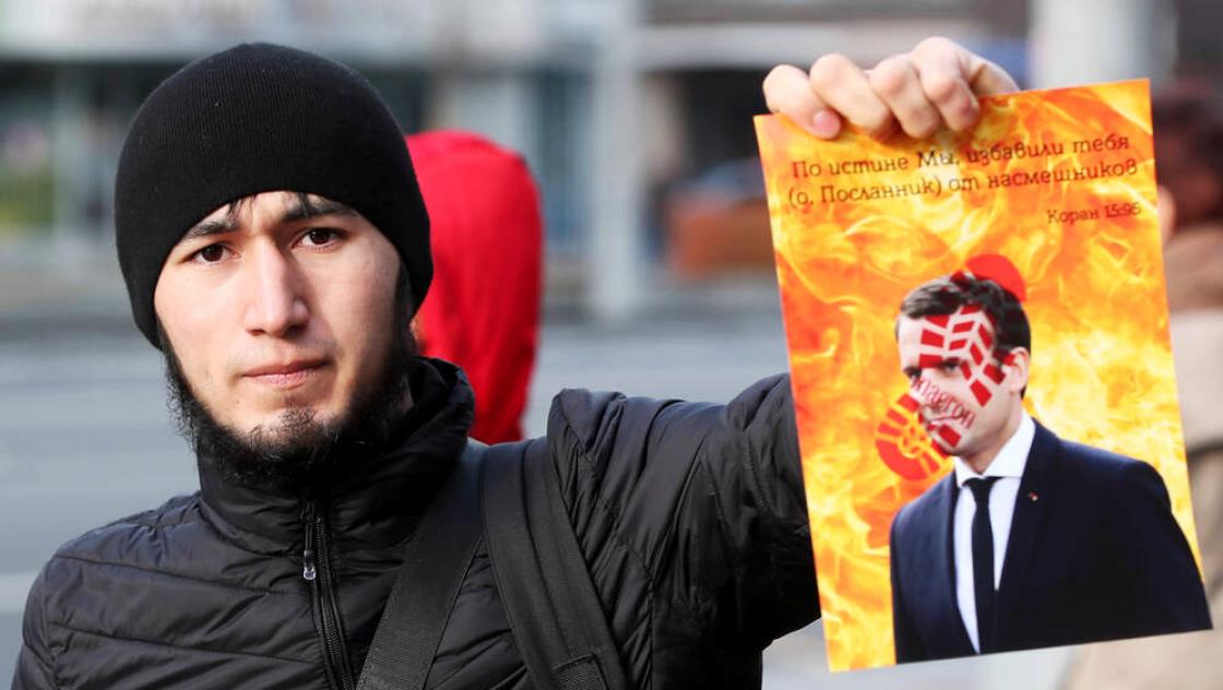 imago images / ITAR-TASS Ein Mann hält ein Porträt des französischen Präsidenten Emmanuel Macron in der Hand, als er an einem muslimischen Protest gegen Frankreichs Präsidenten Emmanuel Macron teilnimmt.