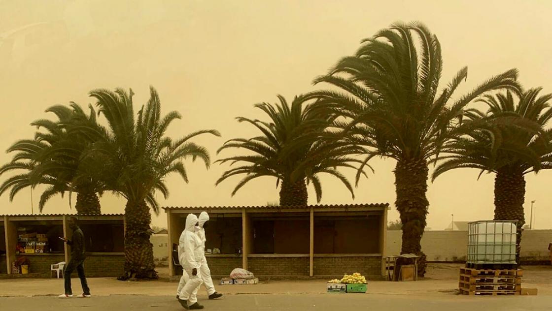 Mitarbeiter der Epidemieprävention während eines Sandsturms in Walvis Bay, Namibia, 18.7.2020 (IMAGO / Xinhua)