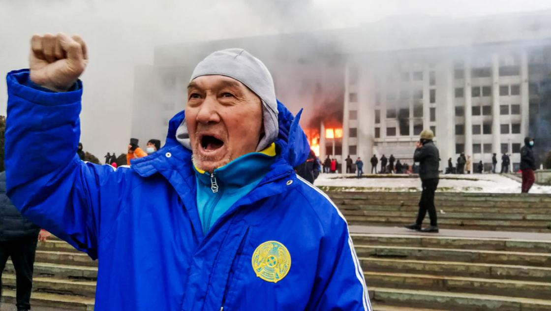 Ein Mann demonstriert vor dem brennenden Büro des Bürgermeisters von Almaty gegen steigende Treibstoffpreise, 5.1.2022 (IMAGO / ITAR-TASS)