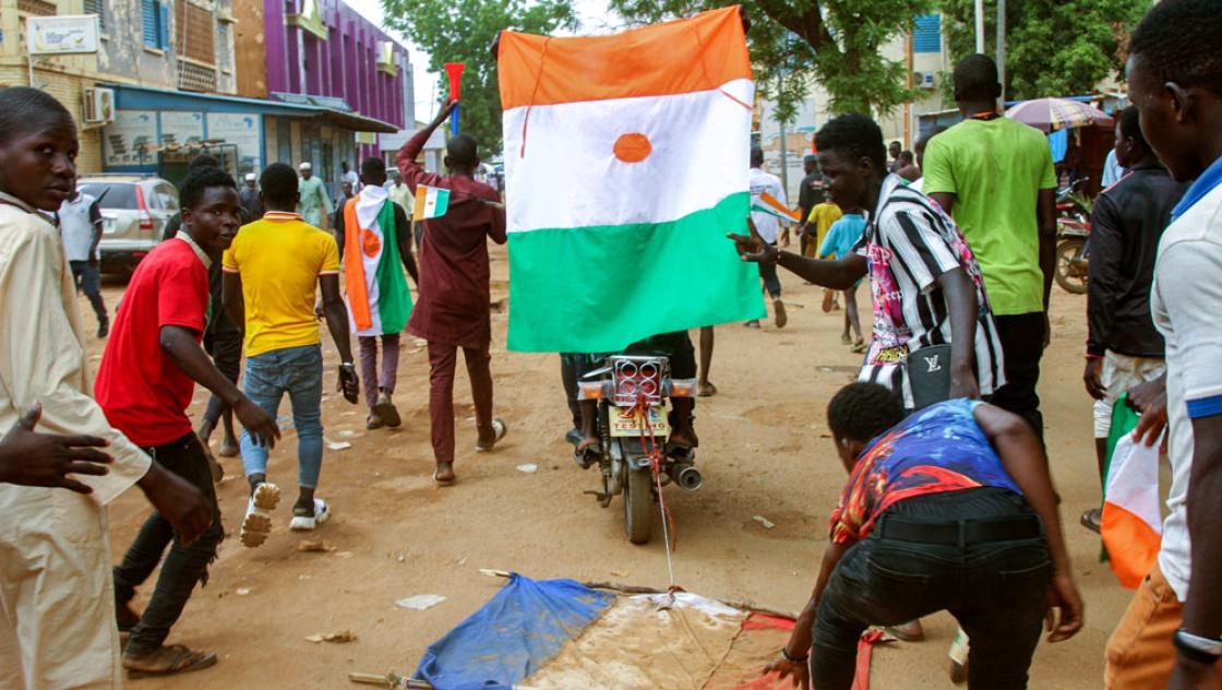 Junge Männer ziehen eine französische Flagge durch den Dreck und schwenken die nigrische Flagge während einer Demonstration nach dem Militärputsch in Niamey, 13.8.2023 (IMAGO / Afrikimages) Junge Männer ziehen eine französische Flagge durch den Dreck und schwenken die nigrische Flagge während einer Demonstration nach dem Militärputsch in Niamey, 13.8.2023 (IMAGO / Afrikimages)