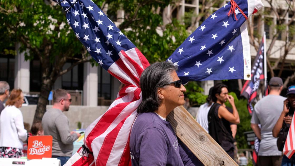 Ein Mann demonstriert mit einem in eine US-Flagge eingewickelten Kreuz in Los Angeles, 10.4.2022 (IMAGO / ZUMA Wire / Ringo Chiu)