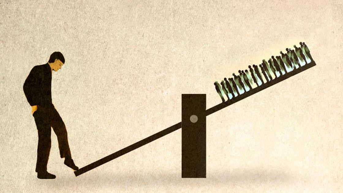 Wippe mit einer großen Person links und vielen kleinen Menschen rechts oben. (IMAGO / Westend61)