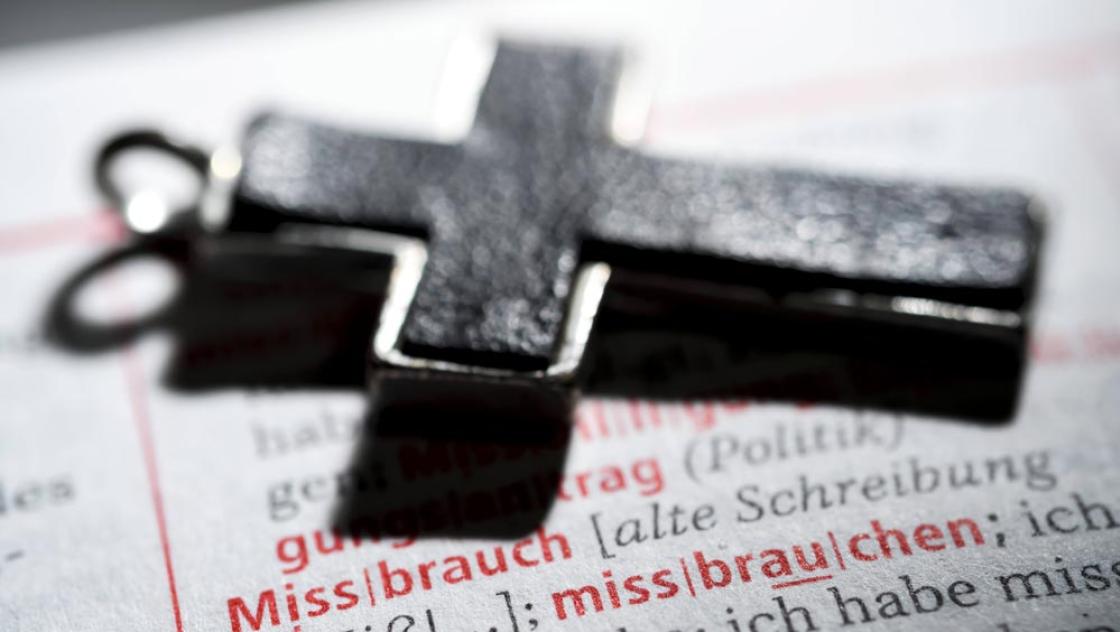 Kreuz auf einem Wörterbuch mit dem Wort »Missbrauch«, Symbolfoto: IMAGO / Christian Ohde