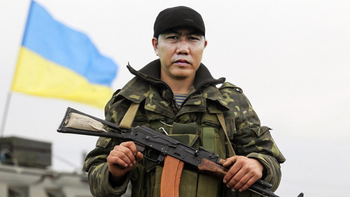 Soldat mit Maschinengewehr, im Hintergrund die ukrainische Flagge