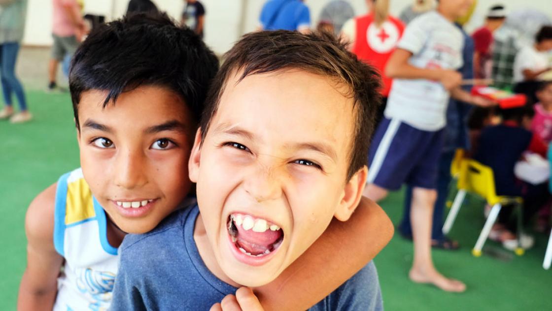 Zu ist ein Junge der den Mund aufgerissen hat und von einem zweiten von hinten umarmt wird