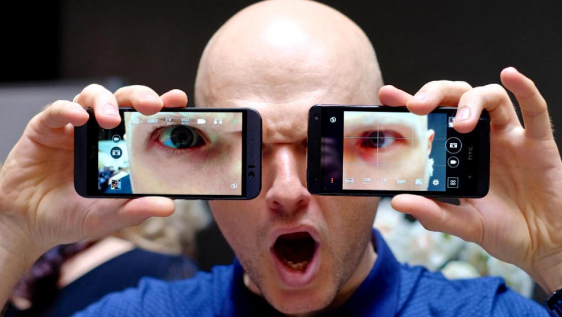 Ein Mann hält zwei Smartphones vor sein Gesicht