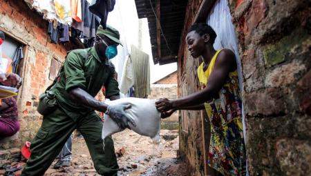 Ein Militäroffizier übergibt am 4. April 2020 während der Verteilung von Nahrungsmitteln in Kampala, der Hauptstadt Ugandas, Lebensmittel an eine Frau.