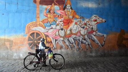 Ein Mann geht während einer landesweiten Abriegelung, die als Präventivmaßnahme gegen die Verbreitung des Coronavirus in Allahabad Prayagraj Indien verhängt wurde, an einem Graffiti eines Gemüsehändlers aus Mahabharat vorbei.