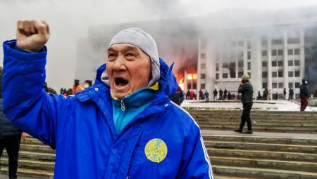 Ein Mann demonstriert vor dem brennenden Büro des Bürgermeisters von Almaty gegen steigende Treibstoffpreise, 5.1.2022 (IMAGO / ITAR-TASS)