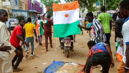 Junge Männer ziehen eine französische Flagge durch den Dreck und schwenken die nigrische Flagge während einer Demonstration nach dem Militärputsch in Niamey, 13.8.2023 (IMAGO / Afrikimages)