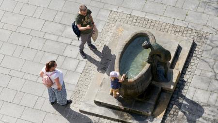 Eine Familie an einem Brunnen im Stadtzentrum von Magdeburg, 25.6.2022 (IMAGO / Panthermedia)