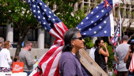 Ein Mann demonstriert mit einem in eine US-Flagge eingewickelten Kreuz in Los Angeles, 10.4.2022 (IMAGO / ZUMA Wire / Ringo Chiu)