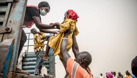 Ein Kind wird in einen Lastwagen gehoben, der Menschen, die vor dem Krieg im Sudan fliehen, nach Renk im Südsudan bringt. Der Krieg im Sudan, der im April 2023 begann, hat zu einer der größten Vertreibungskrisen der Welt geführt. Joda, Sudan, 20.3.2024 (IMAGO / SOPA Images / Sally Hayden)