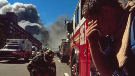 Feuerwehrleute in New York am 11.9.2002. Im Hintergrund sieht man dichte Rauchwolken (IMAGO / United Archives International)