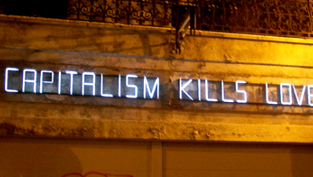 An einer Mauer steht auf Lettern aus Neonröhren: Capitalism kills love
