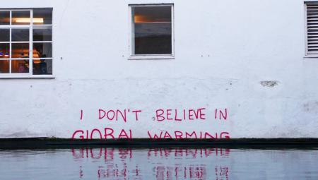 Eine Hauswand mit dem Schriftzug "I don't believe in global warming"