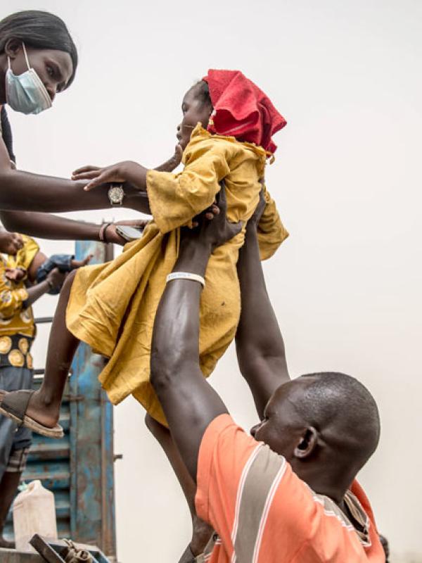 Ein Kind wird in einen Lastwagen gehoben, der Menschen, die vor dem Krieg im Sudan fliehen, nach Renk im Südsudan bringt. Der Krieg im Sudan, der im April 2023 begann, hat zu einer der größten Vertreibungskrisen der Welt geführt. Joda, Sudan, 20.3.2024 (IMAGO / SOPA Images / Sally Hayden)
