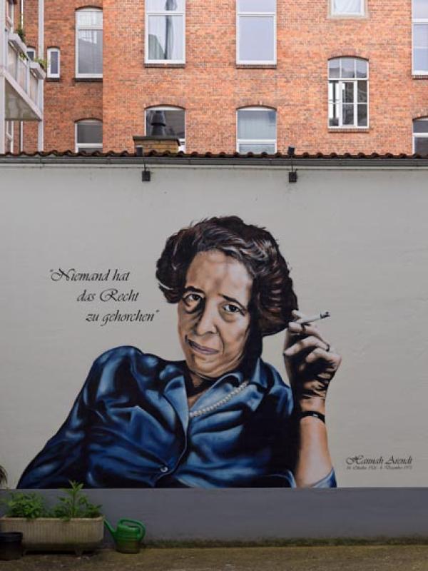 Porträt von Hannah Arendt im Innenhof ihres Geburtshauses. Hannes Grobe (2024) via Wikimedia. Bild zugeschnitten. CC-BY-SA-4.0|https://commons.wikimedia.org/wiki/File:Hannah-arendt3_hg.jpg|