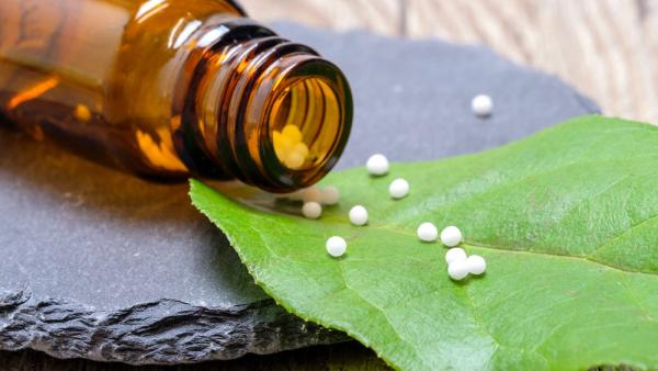 Globuli-Kügelchen neben einer braunen Flasche