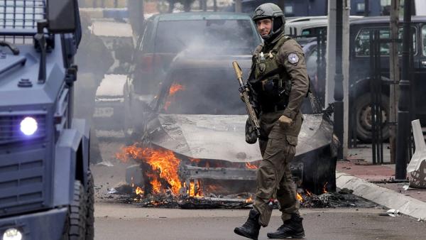 Ein Mitglied einer kosovarischen Spezialeinheit vor einem brennenden Auto in Zvečan. Zuvor gab es Ausschreitungen, 26.5.2023 (IMAGO / Pixsell / Stringer)