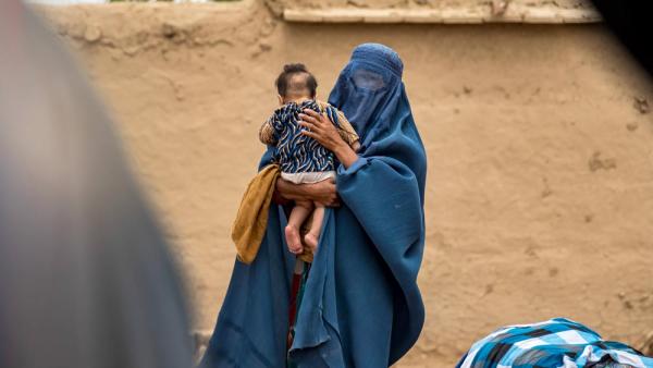 Eine Frau hält ein Kleinkind auf dem Arm. Überschwemmungen haben mehrere Dörfer im Norden Afghanistans zerstört, 15.5.2024 (IMAGO / Middle East Images / Osman)