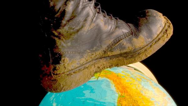 Symbolbild: Ein Stiefel tritt auf einen Erdball (IMAGO / blickwinkel)