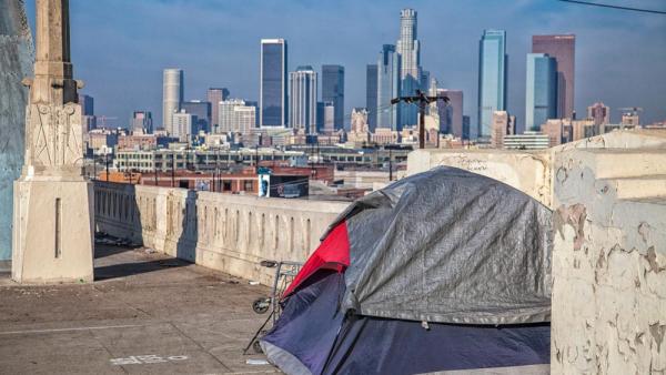 Eine lähmende Bürokratie führt laut Ezra Klein und Derek Thompson im reichen Kalifornien zu einem unnötigen Wohnungsmangel. Zu sehen ist ein Zelt vor der Skyline von Los Angeles, 27.1.2024 (IMAGO / Newscom World / Peter Bennett)