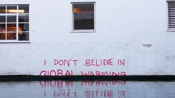 Eine Hauswand mit dem Schriftzug "I don't believe in global warming"